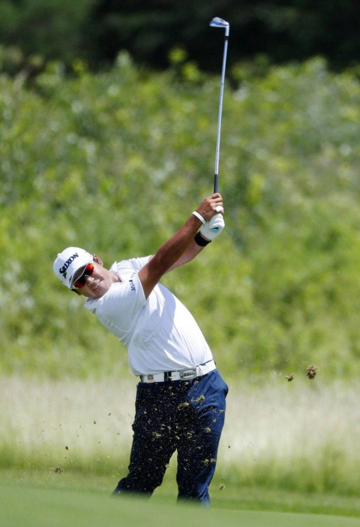 Hideki Matsuyama mid-swing golf action with Srixon cap on lush fairway wallpaper background
