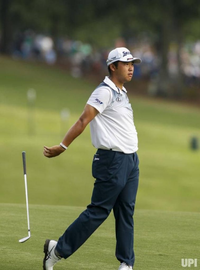 Hideki Matsuyama mid-swing on green fairway intense professional golf wallpaper background