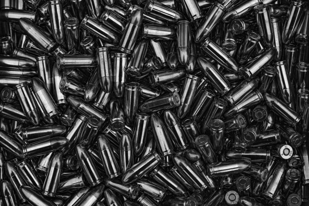 High contrast black and white photo of a chaotic pile of shiny metallic bullets ammunition background Wallpaper