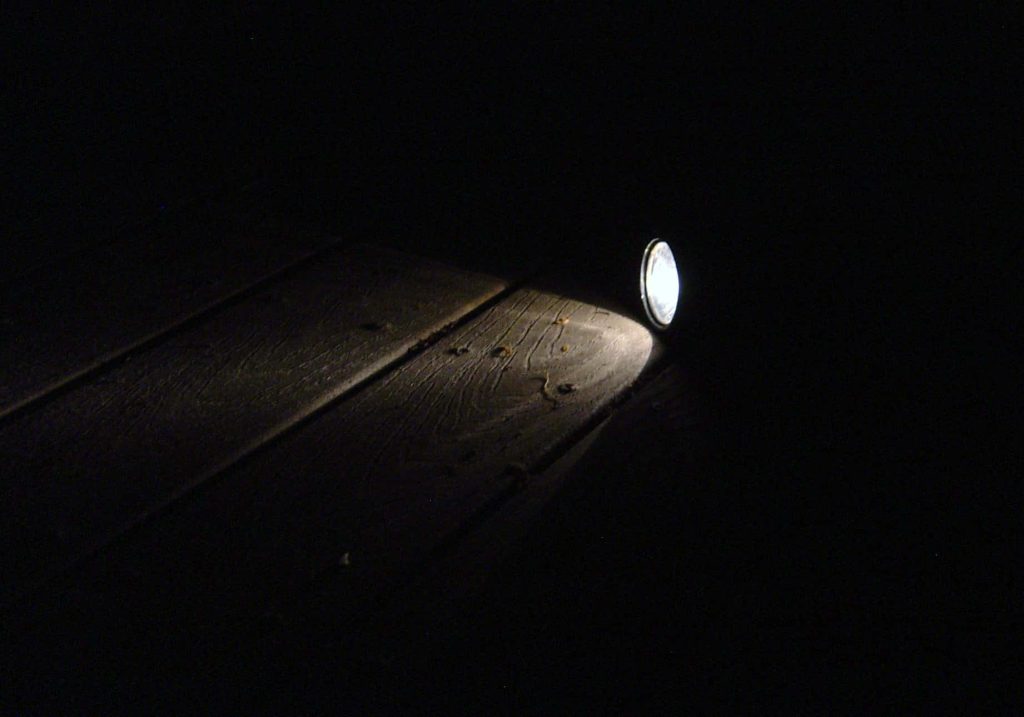 High-contrast flashlight beam illuminating textured wooden planks in dark moody wallpaper background
