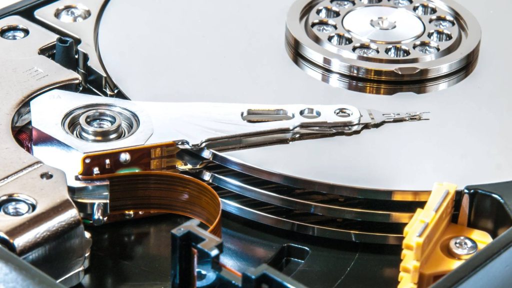 Close-up macro of internal hard disk drive showing magnetic platters and actuator arm details Wallpaper