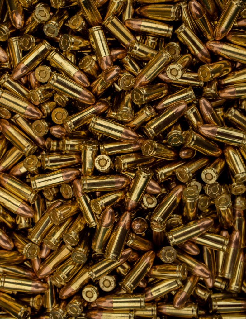 Close-up of shiny brass 9mm bullet cartridges with copper tips textured industrial background Wallpaper