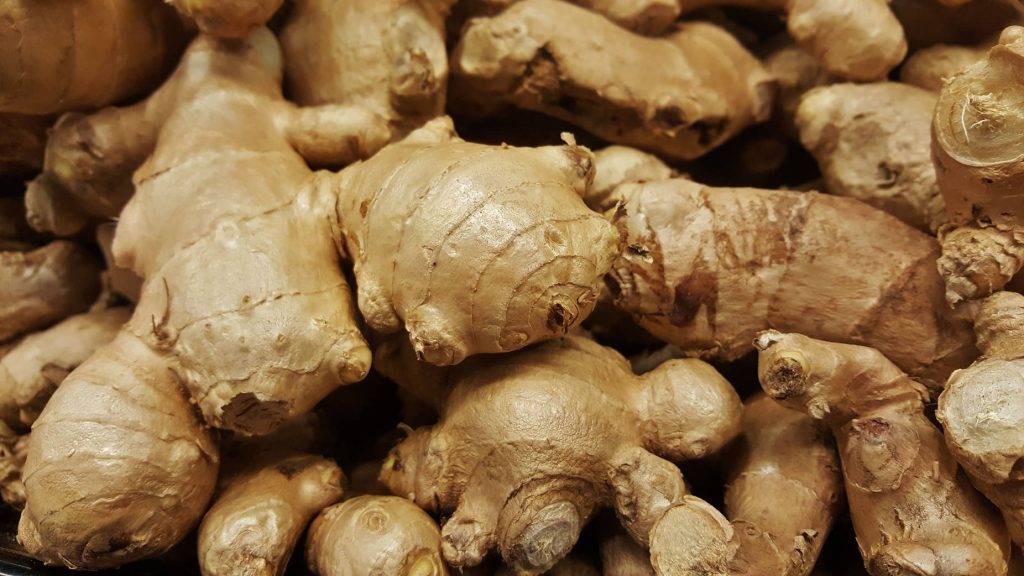 Close-up of fresh raw ginger roots with knobby texture and warm beige tones wallpaper background