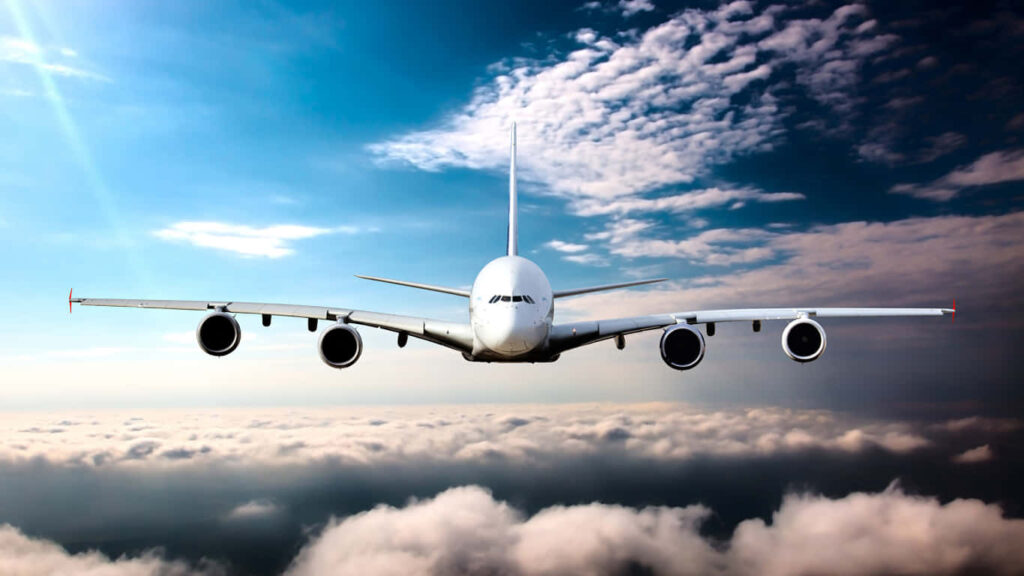 A Majestic Jumbo Jet Takes Flight Through the Clouds in a Daytime Sky Wallpaper