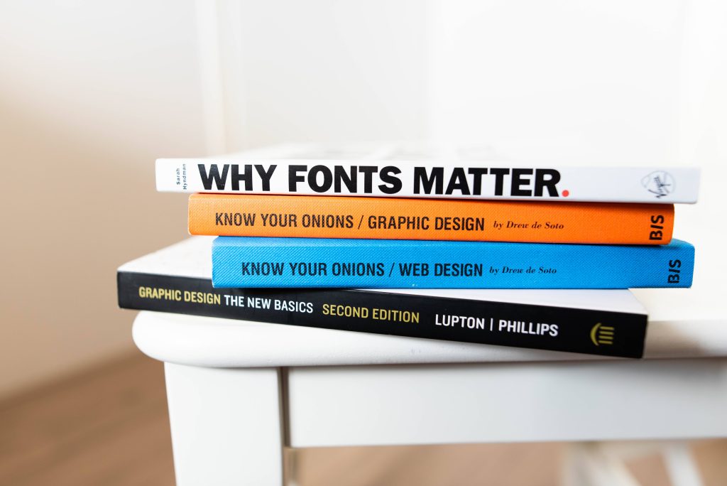 High-key photo of graphic design books stacked titled Why Fonts Matter Know Your Onions and more Wallpaper