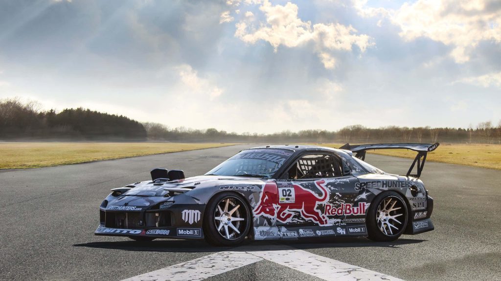 Race-prepped Mazda RX-7 FD with Red Bull livery on open racetrack under dramatic sky wallpaper