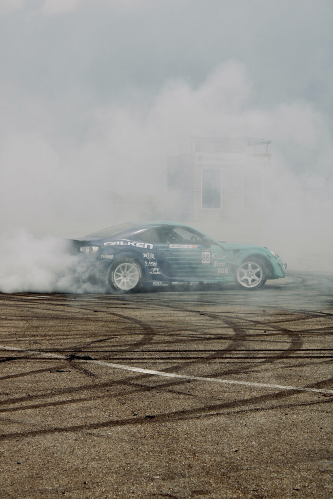 High-performance drift car spinning on sandy track with tire marks and smoke clouds wallpaper
