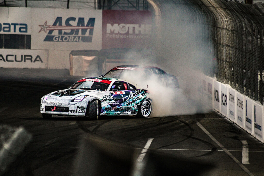 Full HD wallpaper of two drift cars racing with smoke on a professional race track corner