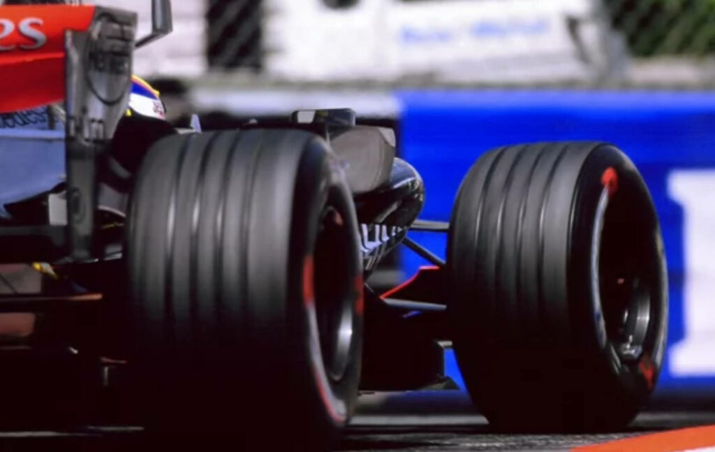 Close-up of Formula 1 car rear tires racing on track in ultra HD showcasing high-performance engineering Wallpaper