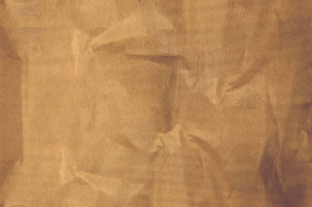 Crumpled brown paper textured wallpaper with detailed folds and soft shadows for workspace background