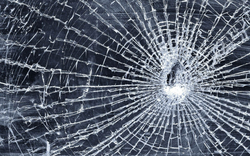 High resolution broken screen wallpaper with spiderweb cracks on dark background digital fragility