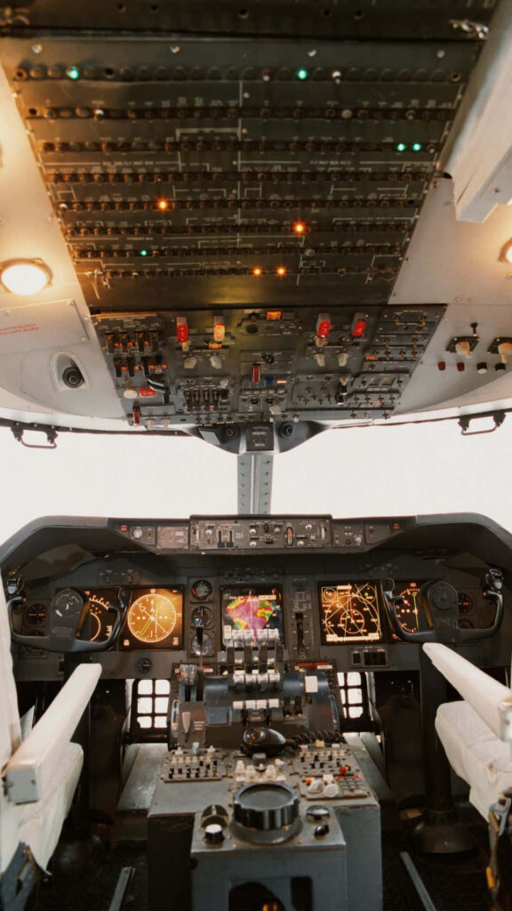 High-resolution commercial airplane cockpit with illuminated controls dials switches and dual seats Wallpaper