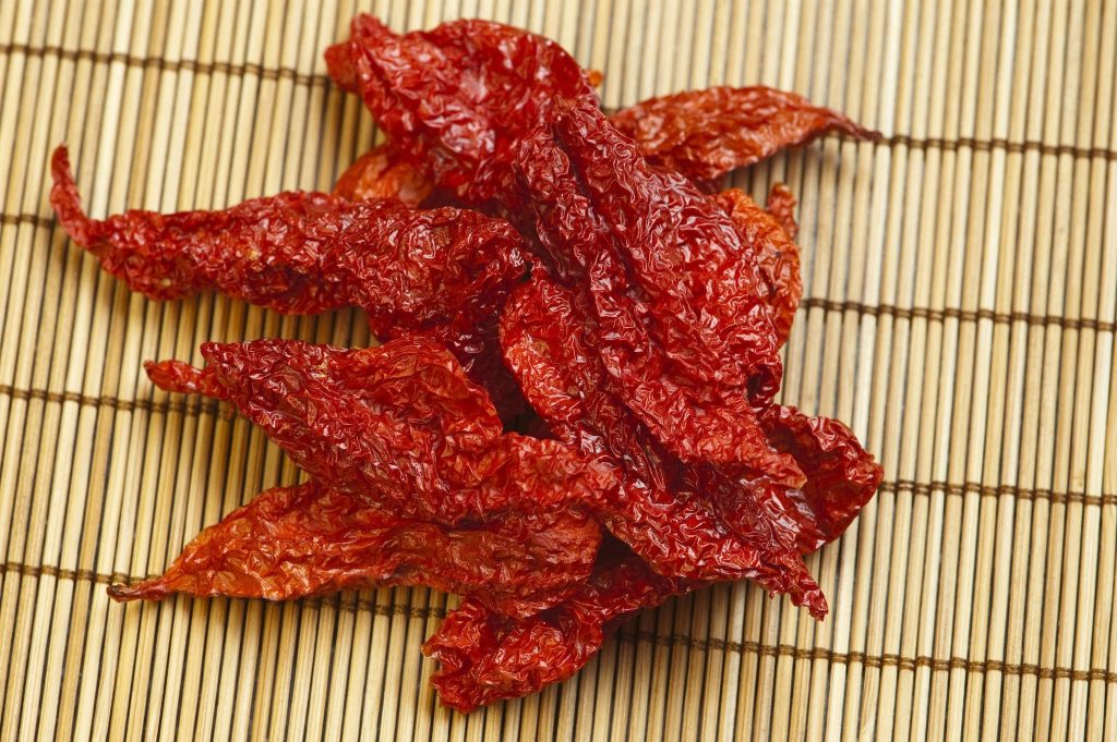 Dried red chili peppers on bamboo mat vibrant textured spice kitchen background wallpaper
