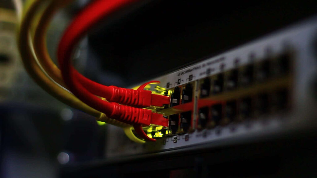 Close-up of network cables with glowing LEDs plugged into a switch vibrant red and yellow tones Wallpaper