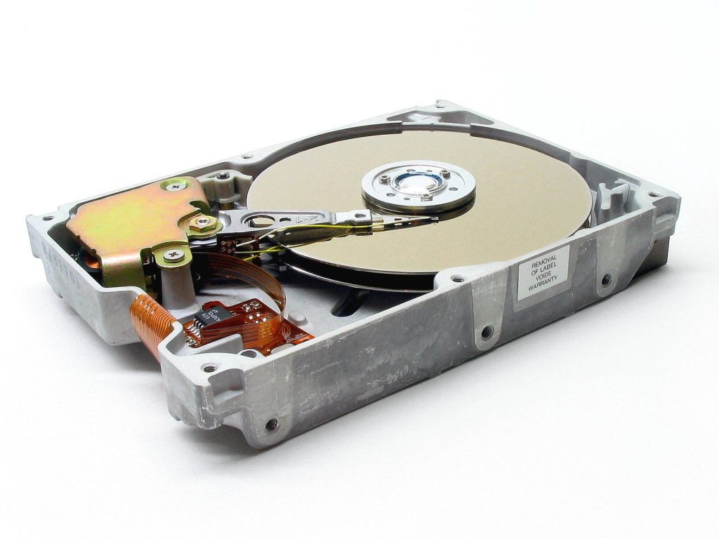 Open hard drive showing shiny disk platter actuator arm and readwrite head closeup Wallpaper