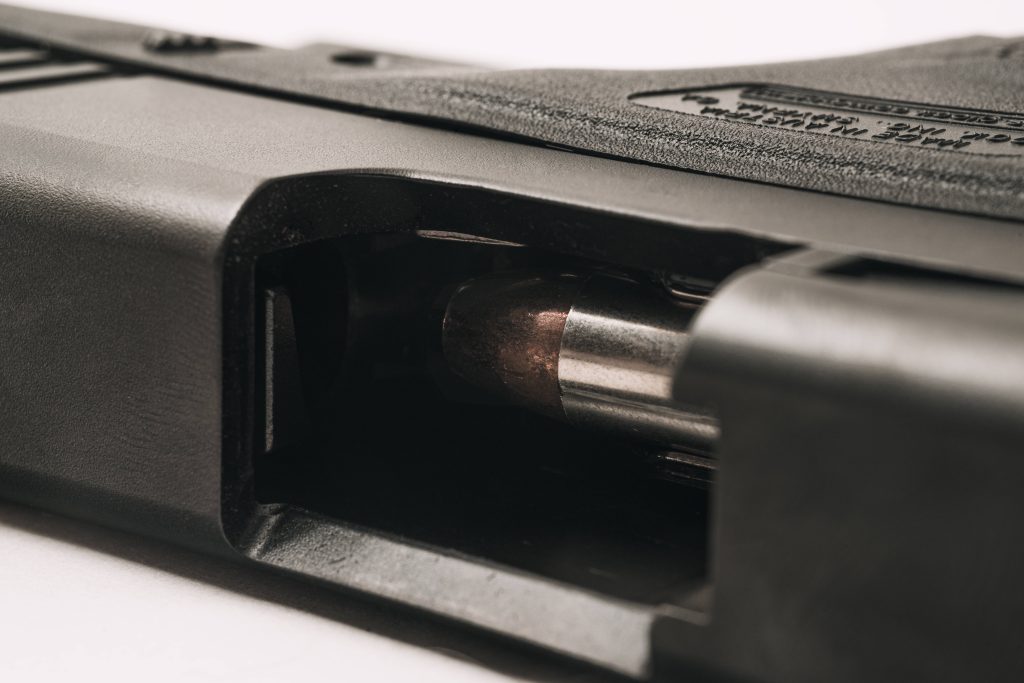 Close-up macro image of Glock pistol chamber with copper-jacketed bullet in open ejection port Wallpaper