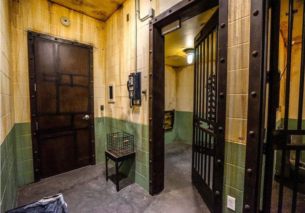 High-resolution prison cell wallpaper with riveted metal doors green cream walls and dim lighting