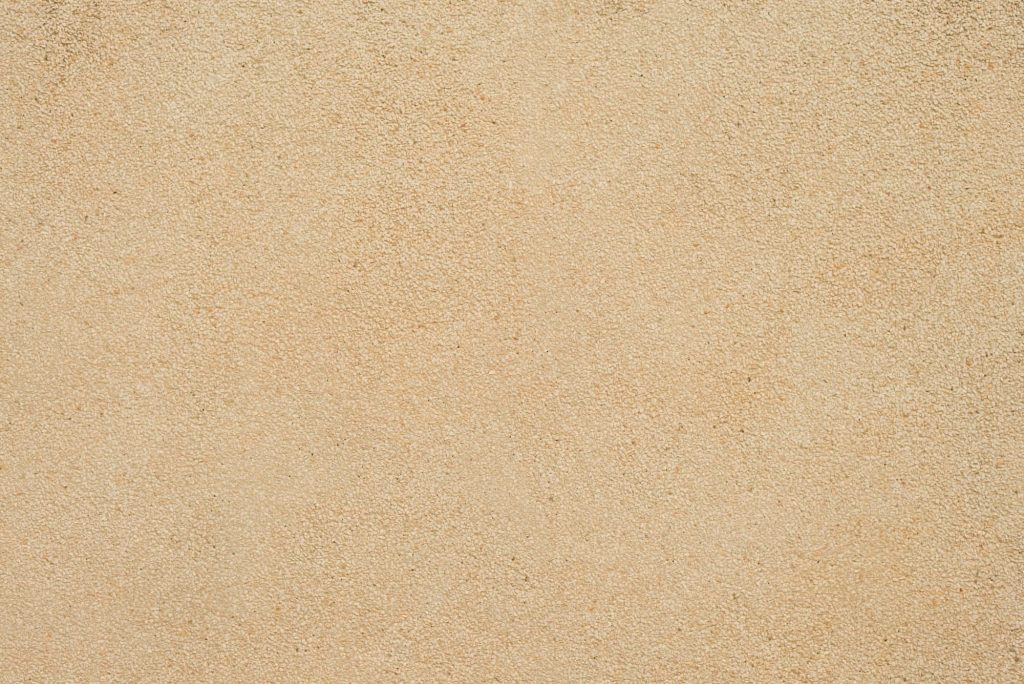 High-resolution sandpaper texture wallpaper in warm beige granular close-up for neutral background
