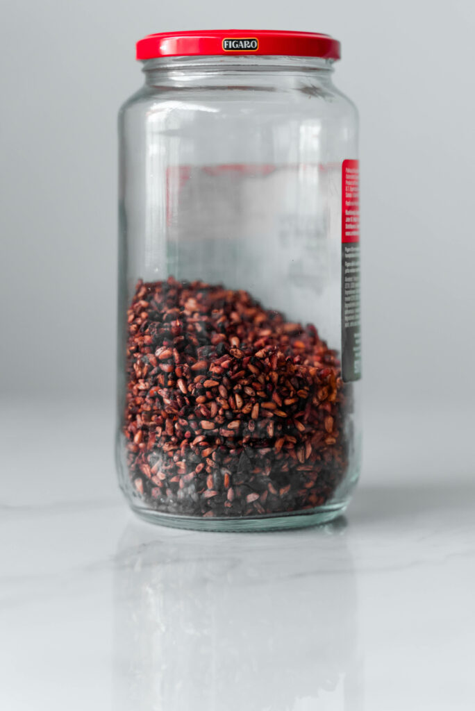 Elegant Wallpaper: Clear Jar of Dried Pomegranate Seeds on Minimalist Background