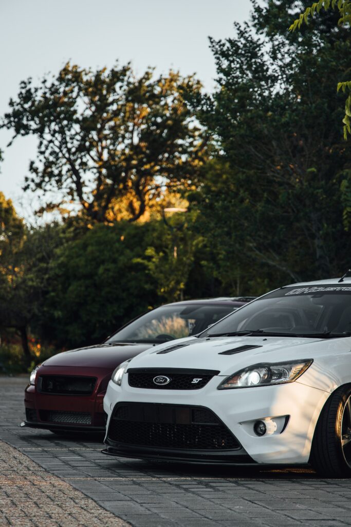 Sleek Cars Outdoors: Sunset Glow & Lush Tree Background Wallpaper
