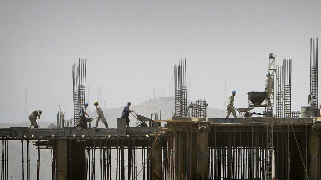 Construction workers building high-rise with steel reinforcements and concrete slabs urban site Wallpaper
