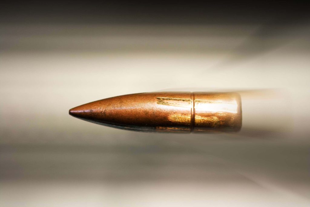 High-speed photo of sharp copper bullet mid-flight with motion blur dynamic wallpaper background