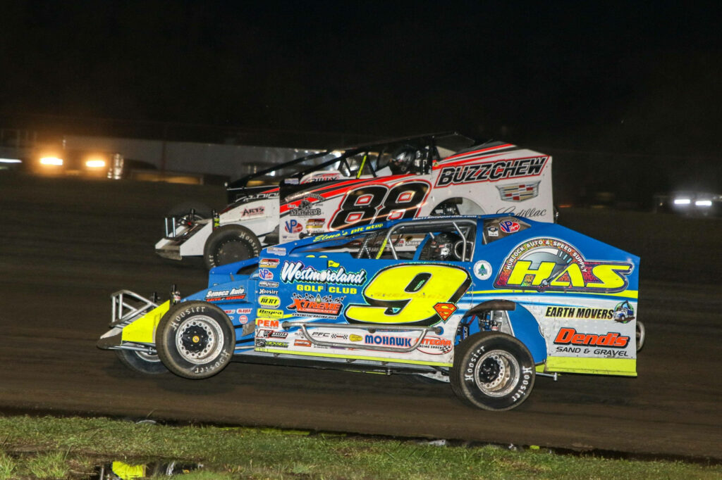 Two colorful dirt race cars speeding side by side on a night track with vibrant decals wallpaper