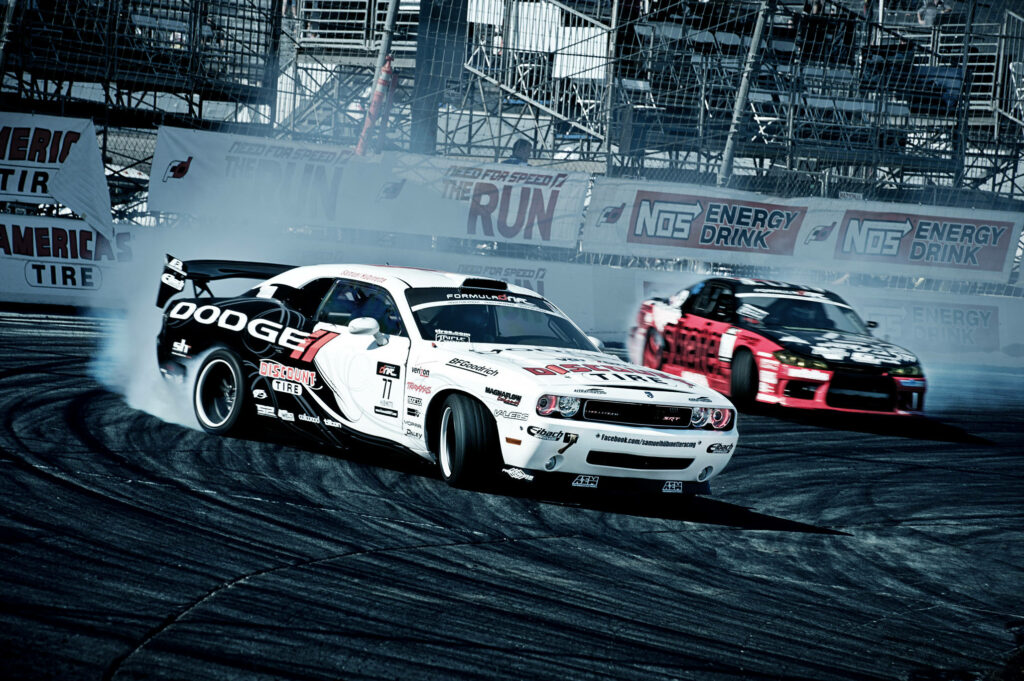 Two powerful cars drifting side by side on racetrack with smoke trails in high-speed race Wallpaper