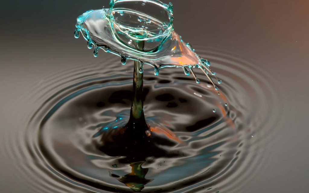 High-speed macro photo of cyan mushroom water drop splash with amber light on dark ripples Wallpaper