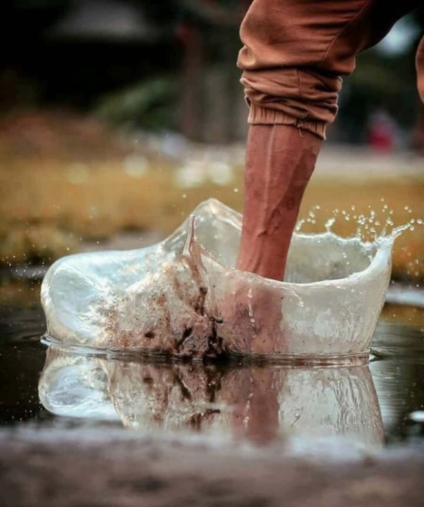 High-speed photo of leg stomping brown trousers creating crystal splash puddle outdoor texture Wallpaper