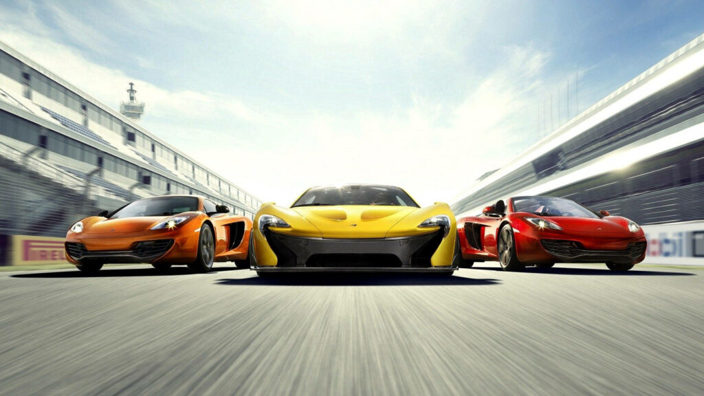 Three sleek sports cars racing side by side on professional track low front angle wallpaper