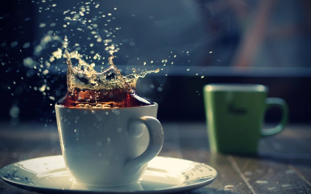 White teacup with tea splash frozen in motion on saucer with dramatic lighting 4K wallpaper