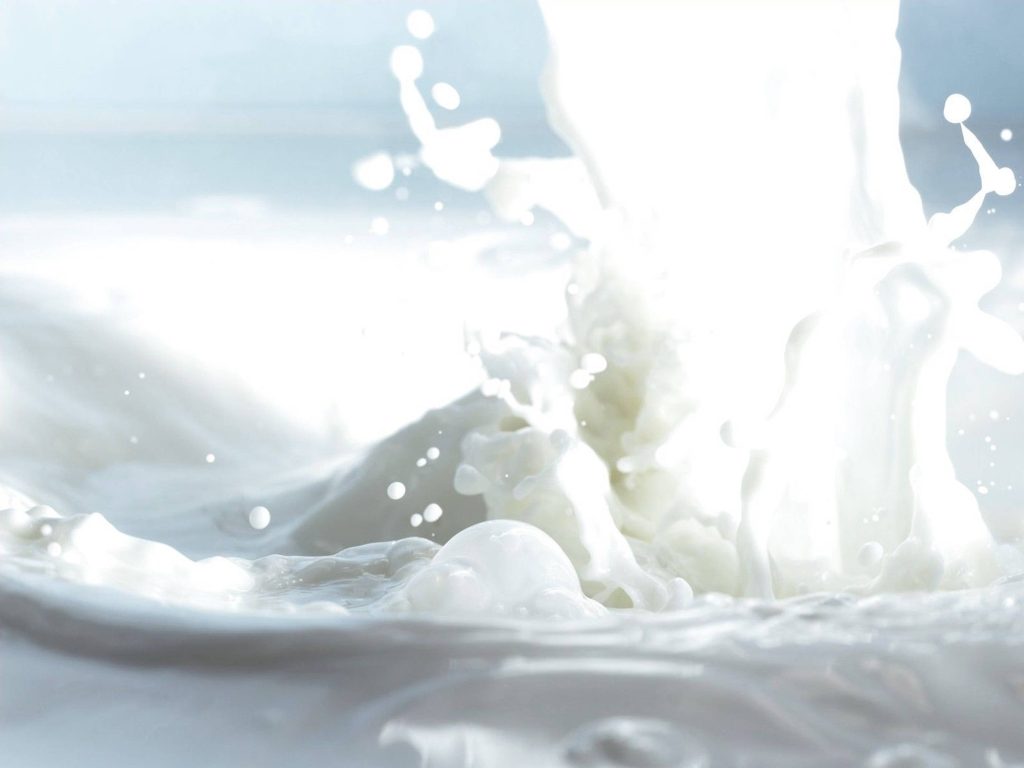 High-speed macro splash of white milk droplets on minimalist bright background wallpaper