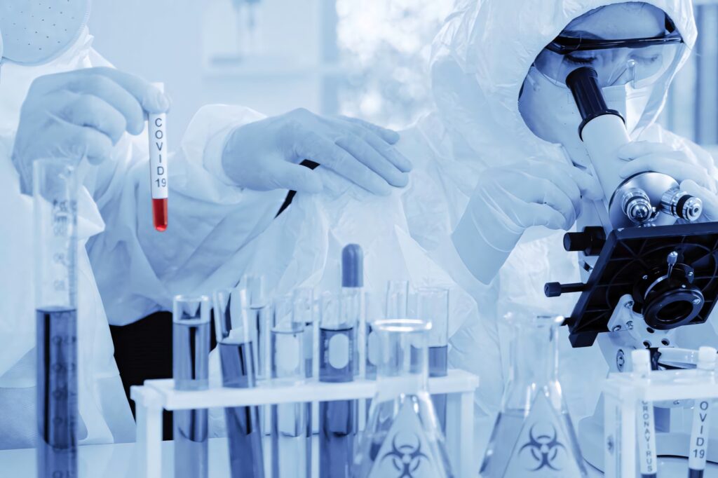 Scientists in protective suits researching COVID 19 in a high tech modern chemistry lab Wallpaper