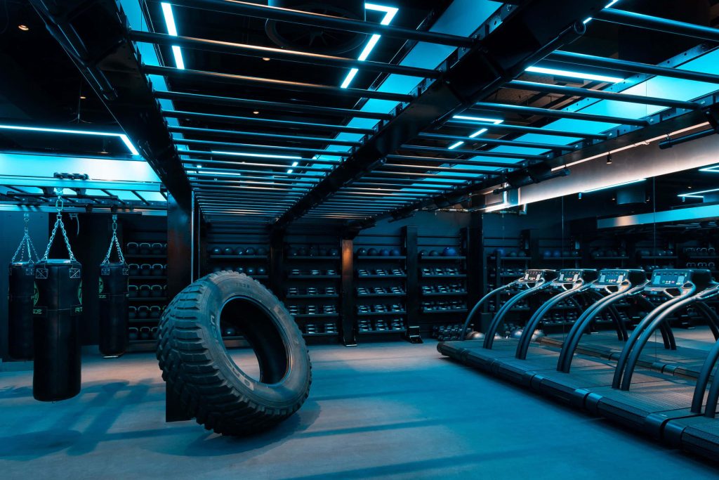 High-tech gym with blue ambient lighting treadmill punching bags monkey bars and tractor tire Wallpaper