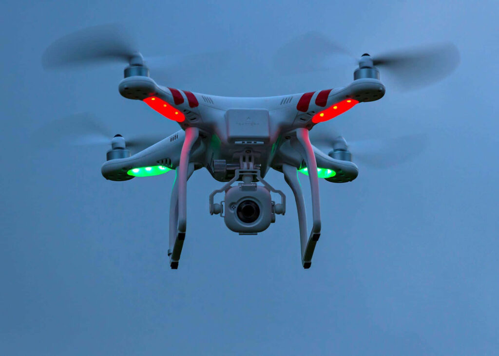 High-tech quadcopter drone with glowing LED lights hovering at dusk for aerial photography Wallpaper