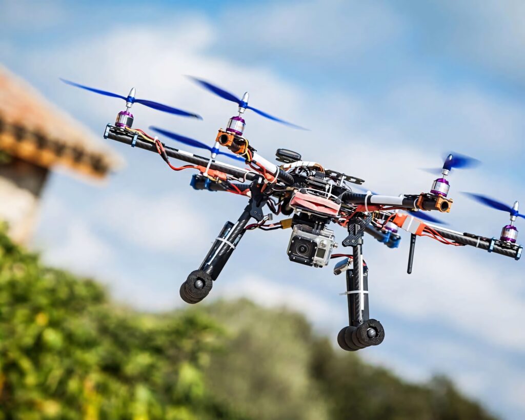 High-tech multi-propeller drone with mounted camera flies in clear blue sky showcasing engineering Wallpaper