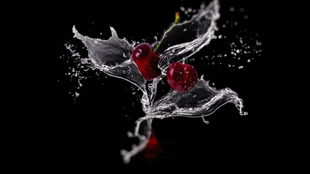 High-speed macro photo of vibrant red cherries with water splash on black background wallpaper