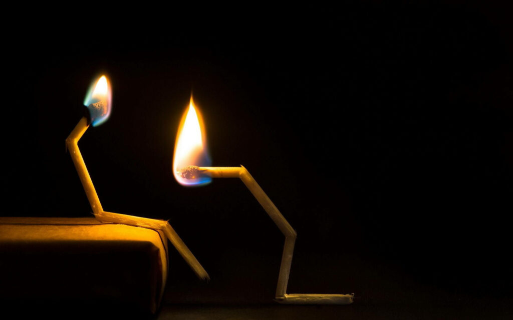 A Comedy of Miniature Fire: Hilarious Match Sticks Radiate on Sleek Black Canvas! Wallpaper