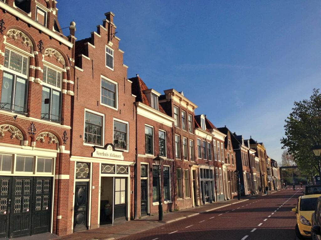 Historic Alkmaar street view with classic Dutch brick facades and sunlit tranquil roadway wallpaper