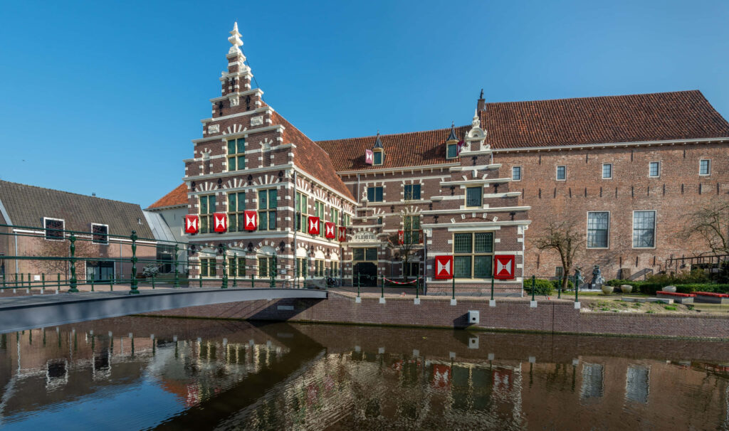 Historical Dutch building in Amersfoort reflected in calm water under clear blue sky wallpaper