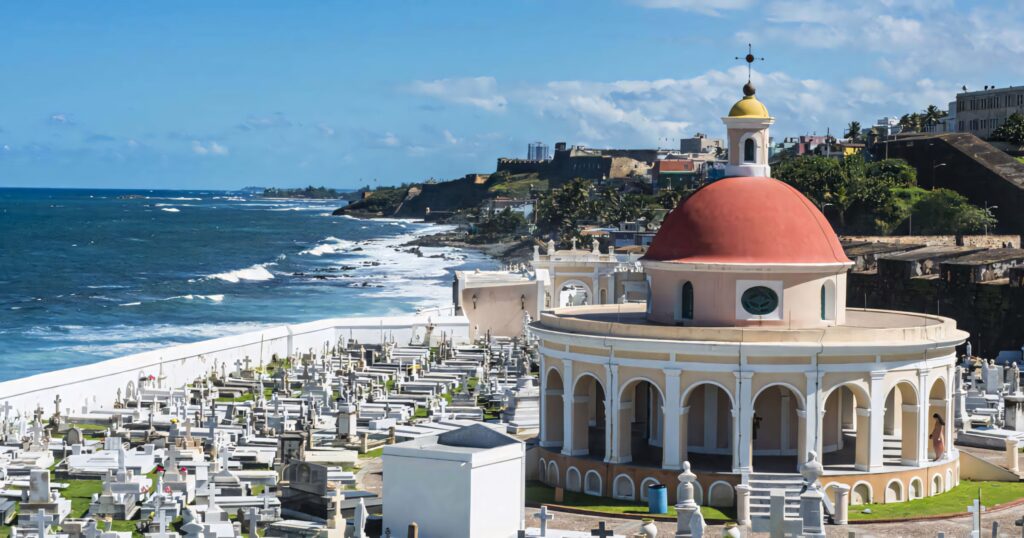 Historic cemetery by Castillo San Felipe del Morro with red dome chapel and blue Atlantic Ocean Wallpaper
