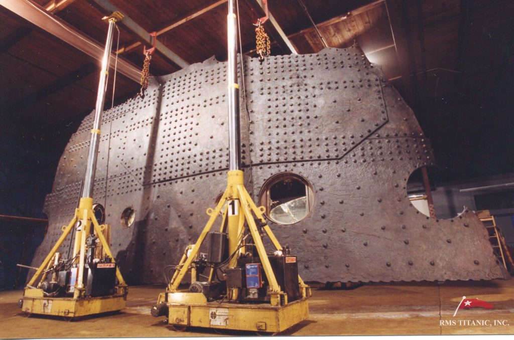 Historic Big Piece of RMS Titanic hull with rivets and portholes lifted by yellow hydraulic cranes Wallpaper