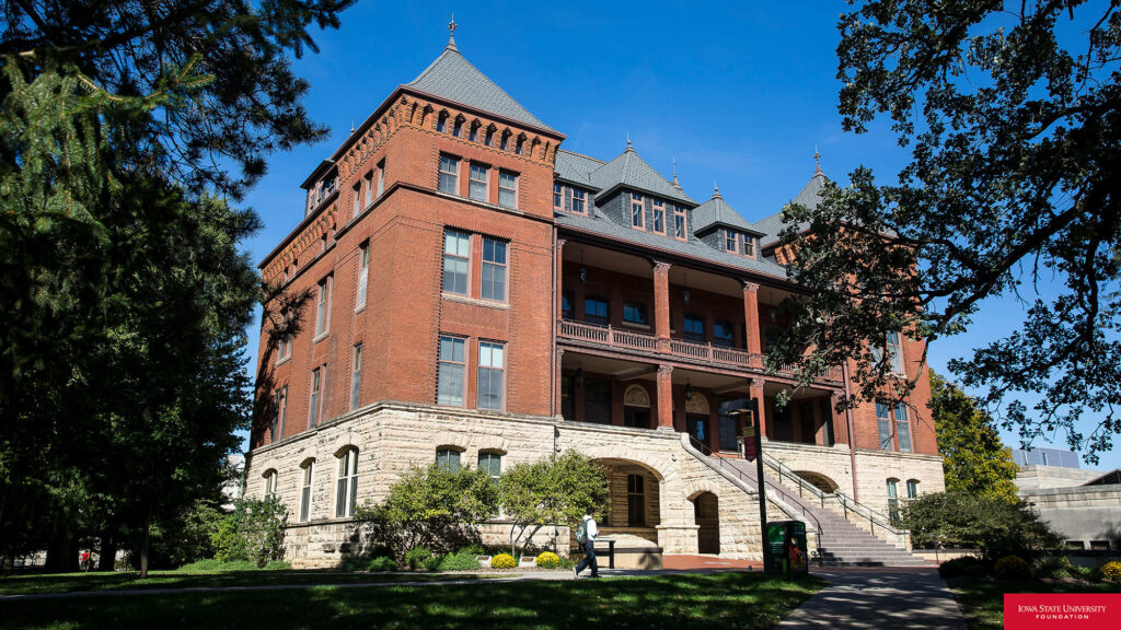 Historic red brick building at Iowa State University with green landscape and clear blue sky Wallpaper
