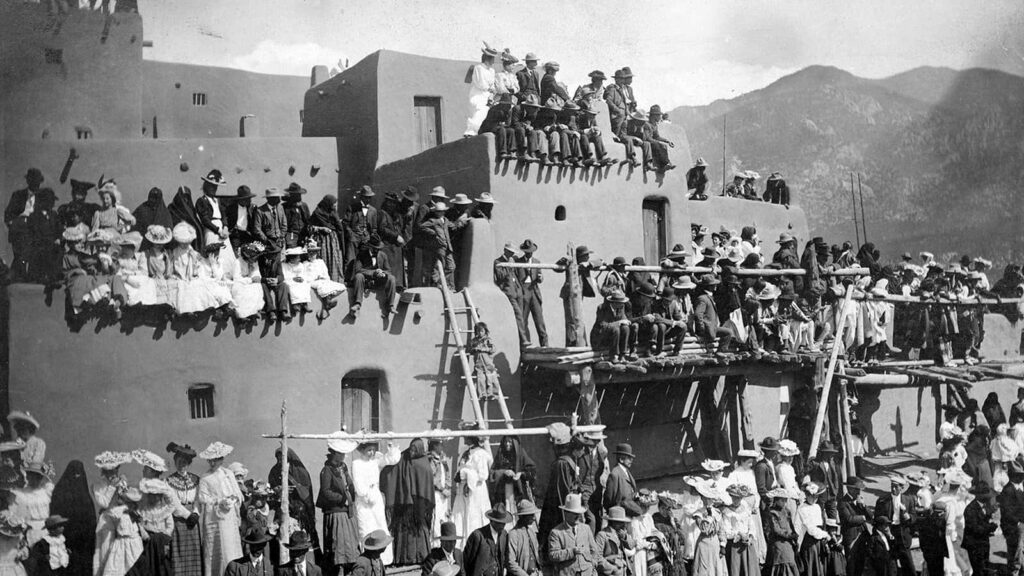 Historic Taos Pueblo Gathering: Multi-Storied Adobe Structures Scene Wallpaper
