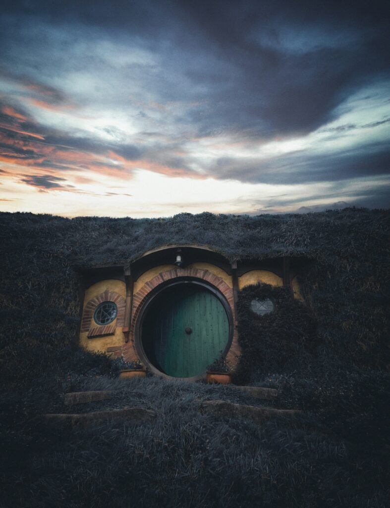 Hobbiton round door nestled in hillside with earthy greens rustic bricks and twilight sky wallpaper