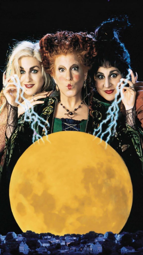 Hocus Pocus Sanderson Sisters casting magic by glowing moon over spooky silhouetted town wallpaper