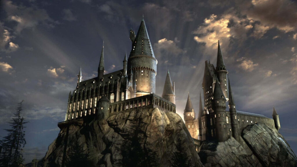 Hogwarts Castle glowing at sunset with dramatic clouds and magical ancient architecture wallpaper