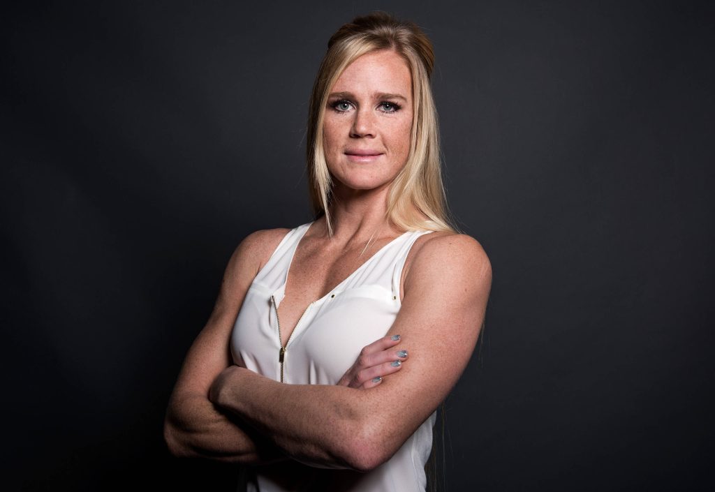 Confident UFC fighter Holly Holm in white sleeveless blouse studio portrait charcoal background Wallpaper