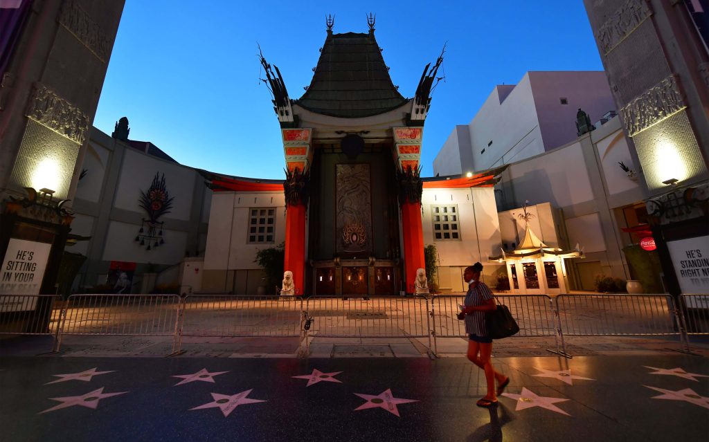 Woman walking by TCL Chinese Theatre Hollywood twilight red pillars Walk of Fame stars Wallpaper
